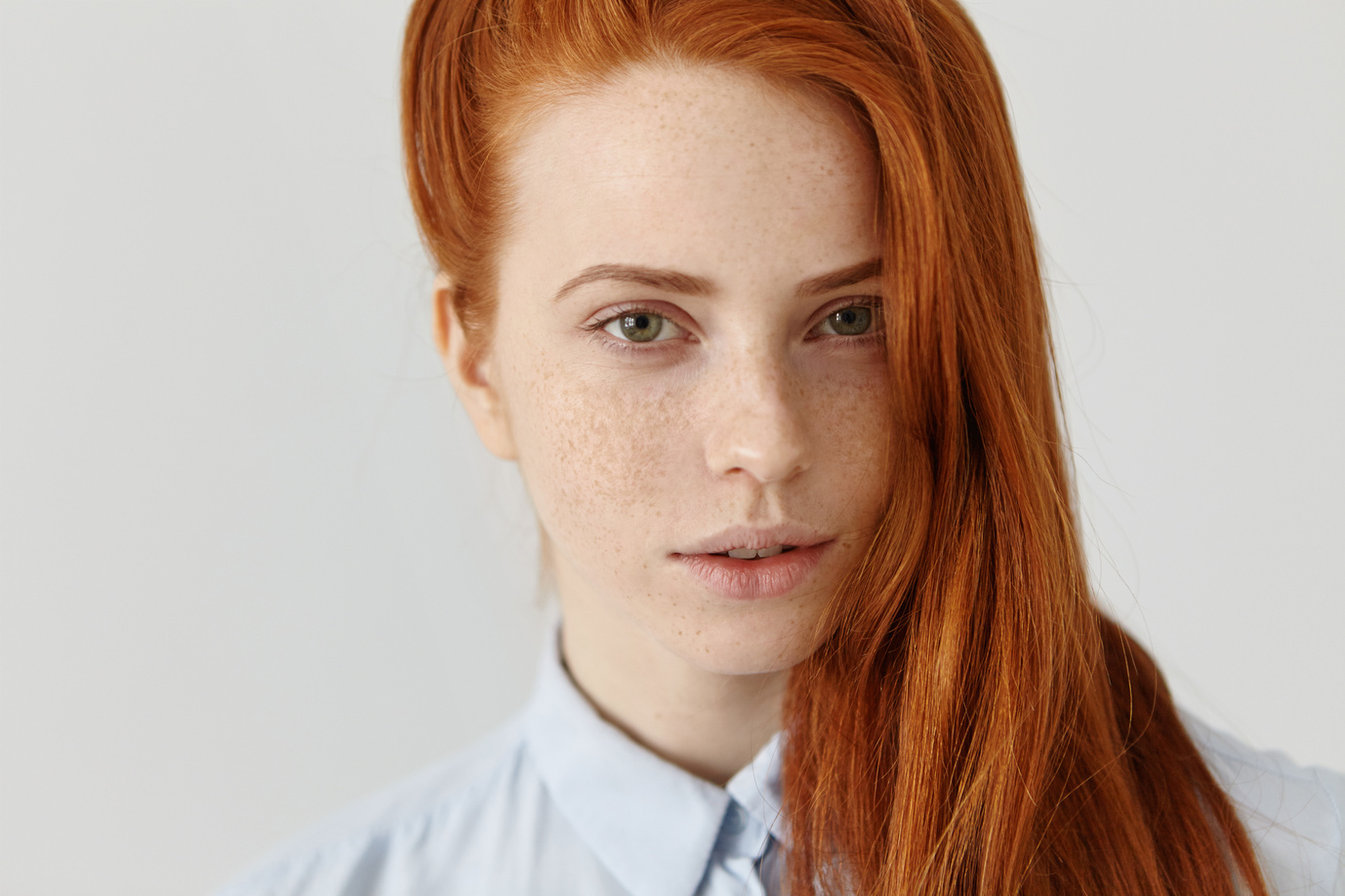 Młoda kobieta w błękitnej koszuli, o intensywnie rudych włosach
