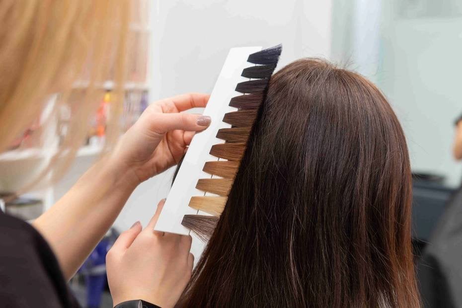 Fryzjerka porównuje próbki koloru do włosów klientki w salonie.