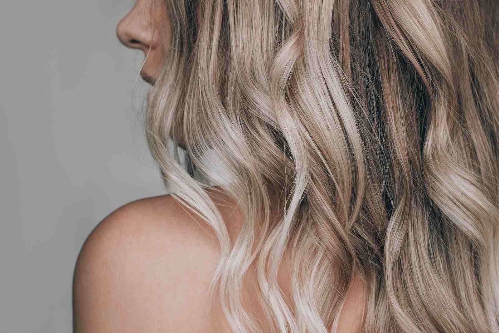 Kobieta z półprofilu i pofarbowane na chłodny blond falowane włosy