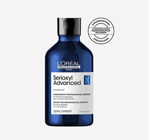 Niebieska butelka szamponu L’Oréal Serioxyl stoi na białym tle, z okrągłą pieczęcią obok.